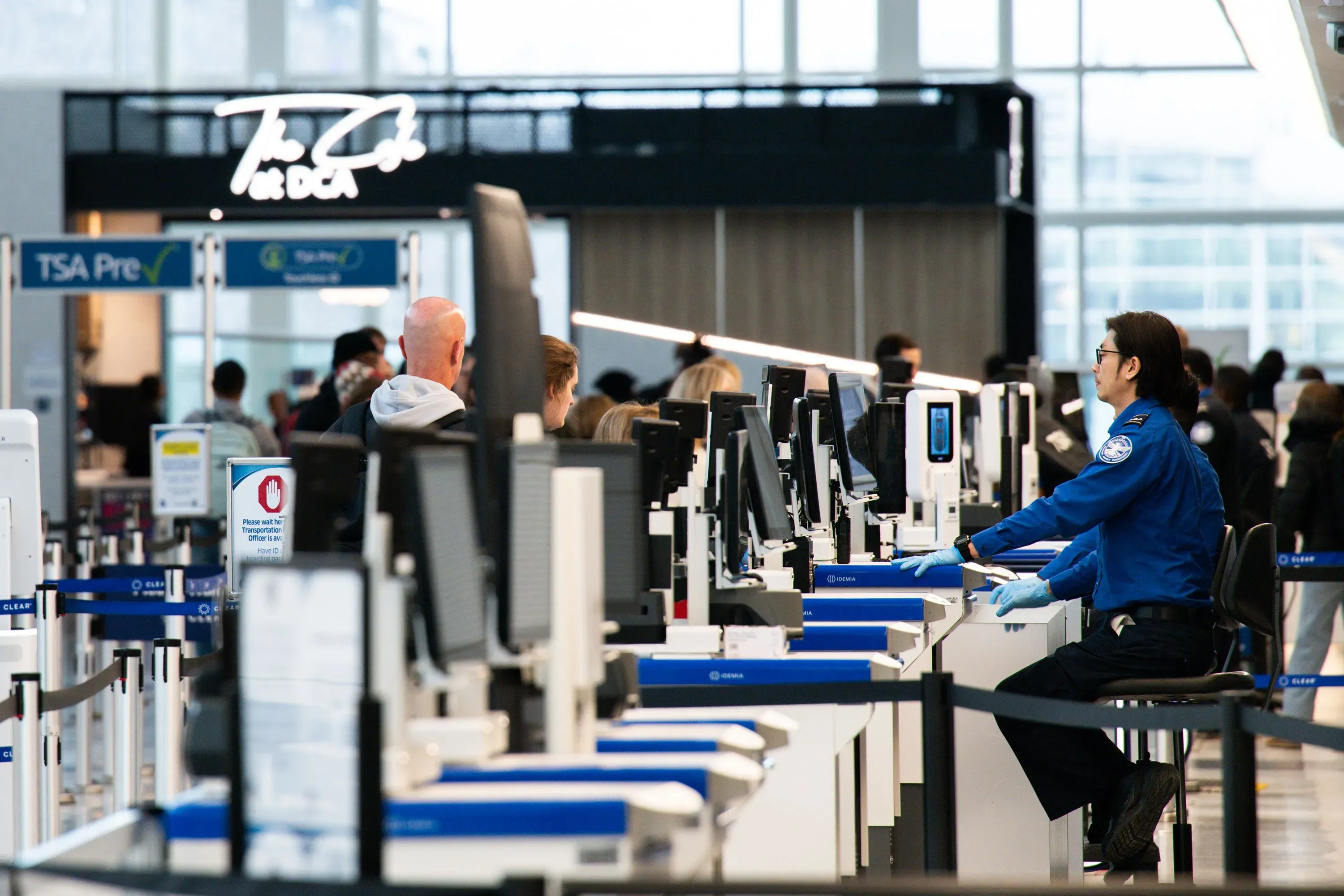 طوابير طويلة في مطار مزدحم، حيث يعمل موظف أمن في إدارة أمن النقل وسط نقص في الموظفين بسبب الإغلاق الجزئي للحكومة.