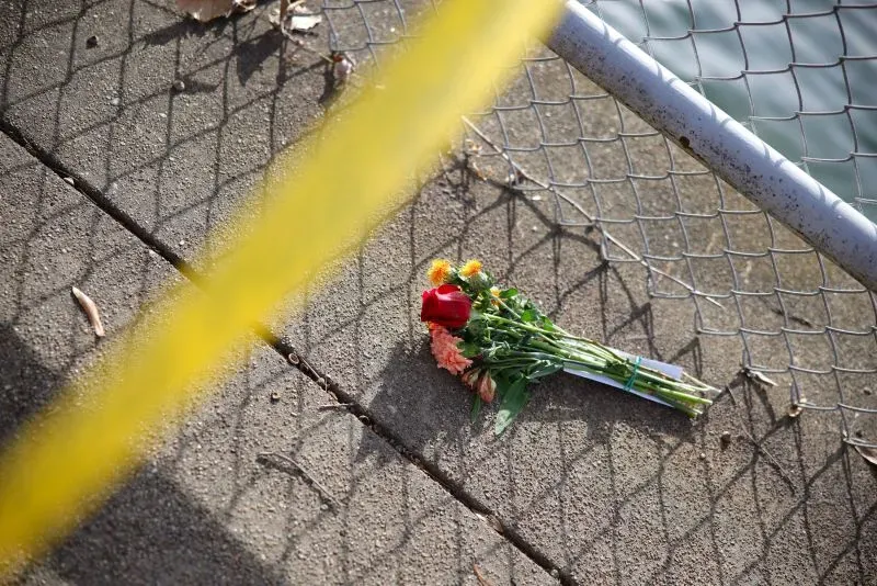 باقة من الزهور ملقاة على الرصيف قرب سياج، تشير إلى الحزن بعد حادث تصادم طائرة بلاك هوك في واشنطن.