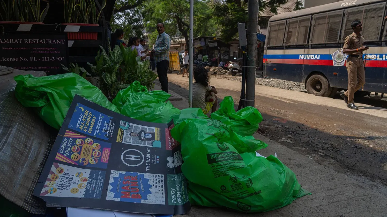 نفايات ملقاة على الرصيف بالقرب من مطعم في مومباي، مع وجود شرطة في الخلفية، تعكس التوترات حول حرية التعبير في الهند.