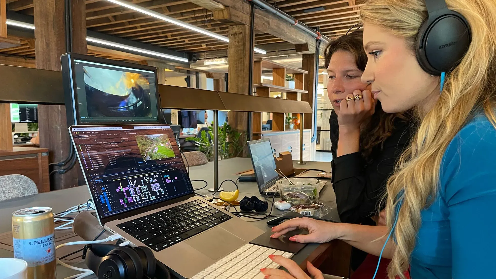 شخصان يعملان على تحرير مقطع فيديو في مكتب حديث، مع شاشة عرض إضافية وأجهزة كمبيوتر محمولة، تعبير عن جهود إنتاج برنامج "ذا إنفوي شو".