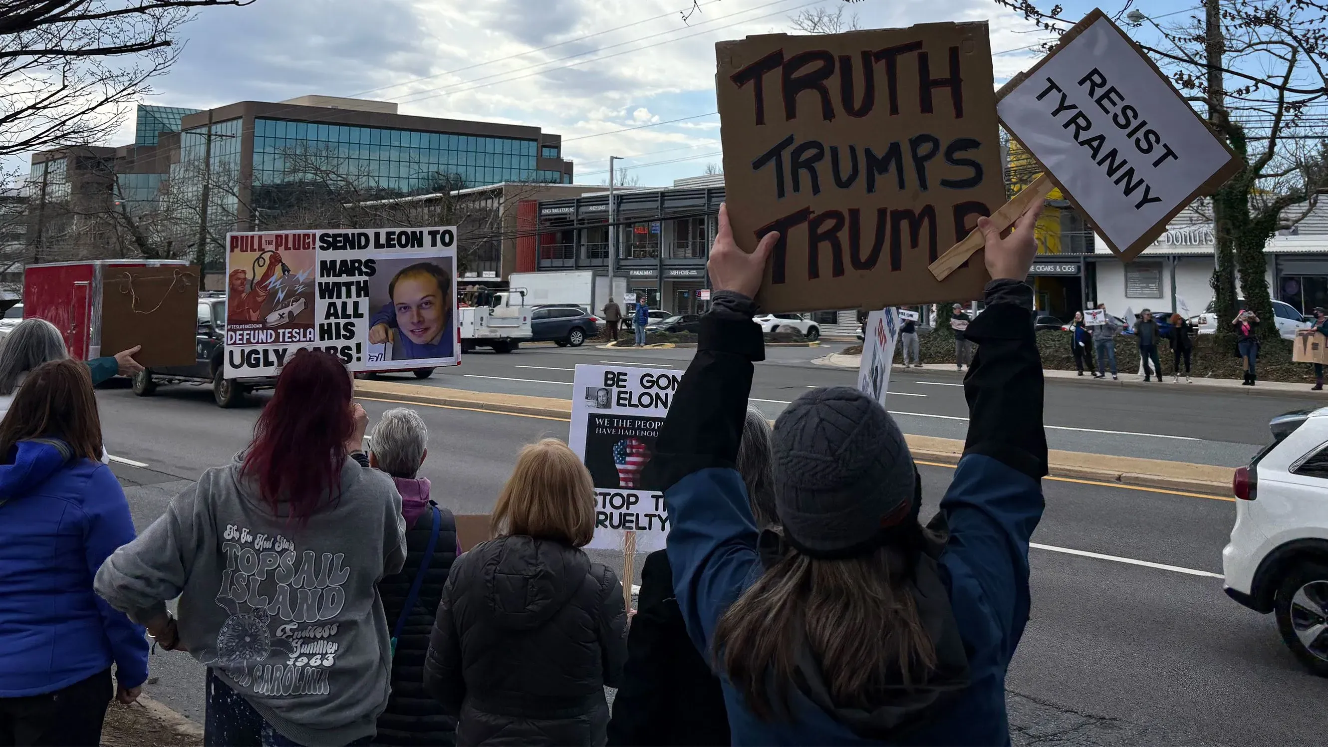 محتجون يحملون لافتات تنتقد إيلون ماسك وتطالب بوقف العنف ضد تسلا، في مشهد يعكس تصاعد الاحتجاجات السلمية في الولايات المتحدة.