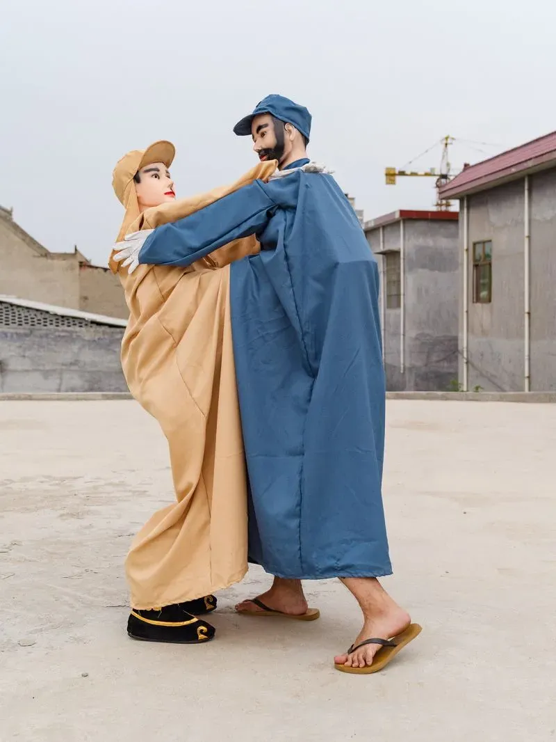زوج من الدمى البشرية dressed in traditional outfits, performing a cultural act in a modern setting, highlighting the contrast between tradition and modernity.