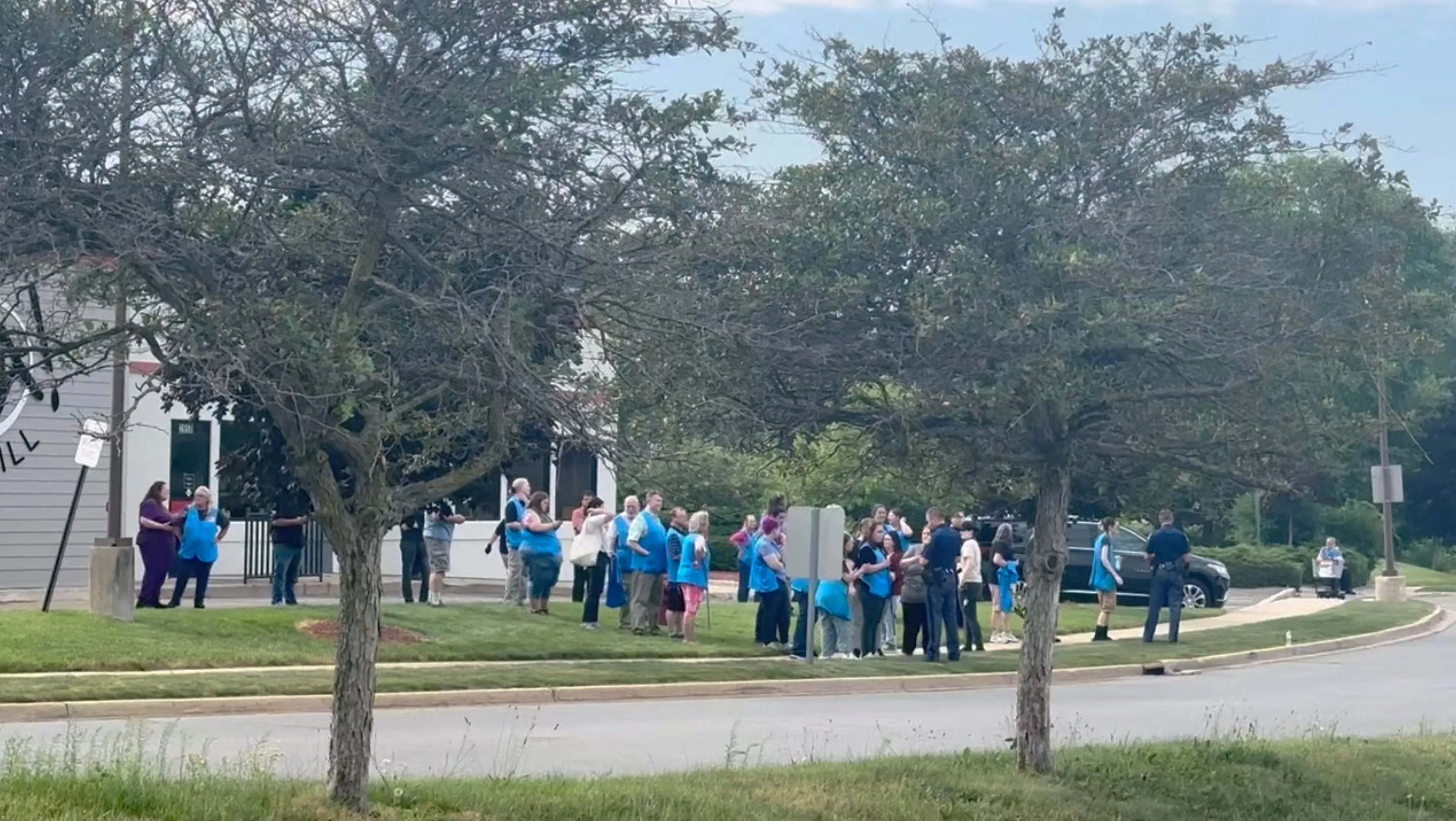 تجمع عدد من الأشخاص في ملابس زرقاء خارج متجر وول مارت في ترافيرس سيتي، ميشيغان، بعد حادث طعن عشوائي.