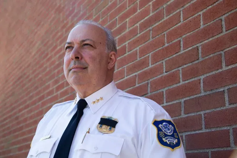 رئيس الشرطة يقف أمام جدار من الطوب، يعبر عن الجدية في التعامل مع قضايا الاعتداء وسوء المعاملة في المجتمع.