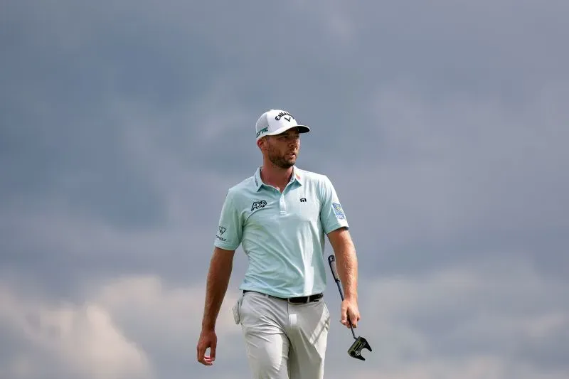 آدم سكوت يتجول في ملعب أوكمونت تحت سماء غائمة، مستعدًا لجولة حاسمة في بطولة الولايات المتحدة المفتوحة.