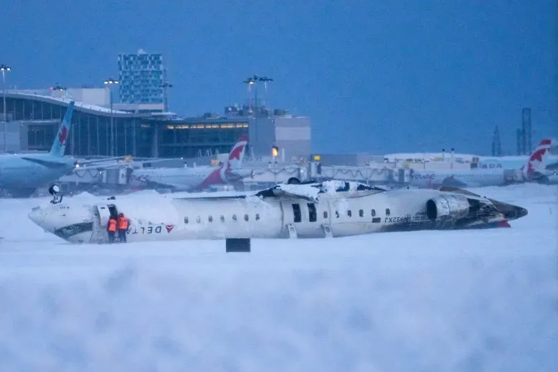 طائرة دلتا متضررة بسبب حادث في مطار، مع وجود فرق الطوارئ في الموقع، تعكس المخاوف المتزايدة بشأن سلامة السفر الجوي.