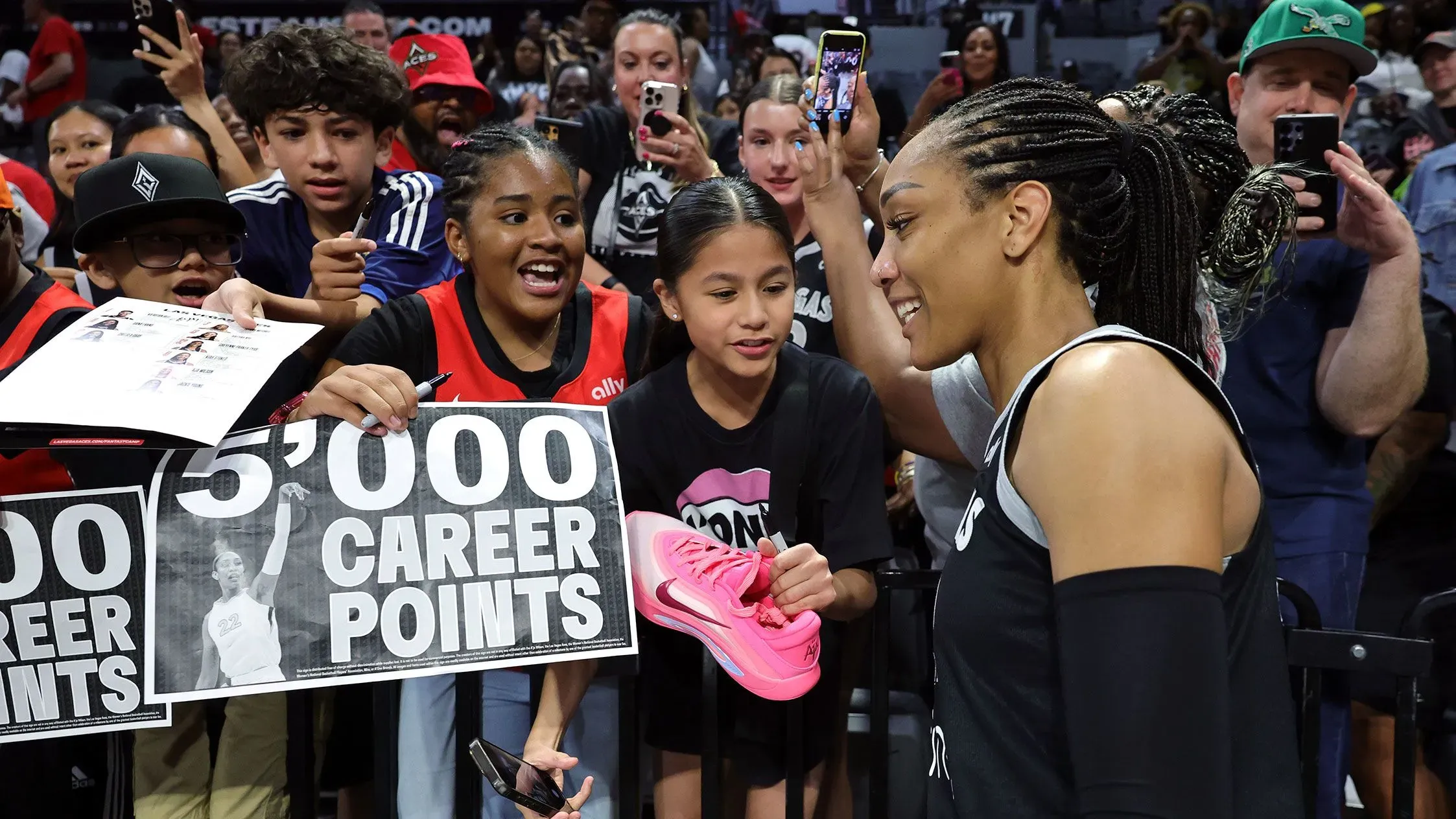 أجا ويلسون تتفاعل مع المعجبين بعد تسجيلها 5000 نقطة في مسيرتها، حيث يحمل الأطفال لافتات احتفالية تعبر عن إنجازها التاريخي.