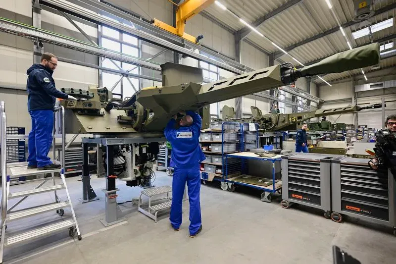 عمال في مصنع يقومون بتجميع معدات عسكرية متطورة، مما يعكس زيادة الإنفاق الدفاعي في أوروبا وتأثيره على الاقتصاد المحلي.