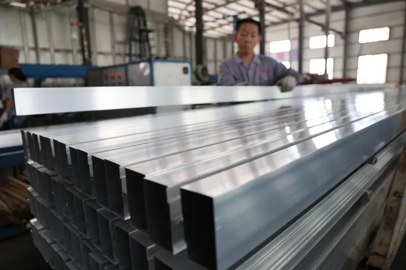 عامل يعمل على معالجة الألواح المعدنية في مصنع، مما يعكس تأثير سياسات ترامب التجارية على الصناعة الأمريكية والوظائف.