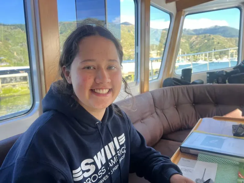 مايا مرهج، السباحة البالغة من العمر 17 عامًا، تبتسم داخل قارب دعم أثناء استعدادها لعبور مضيق كوك في نيوزيلندا.