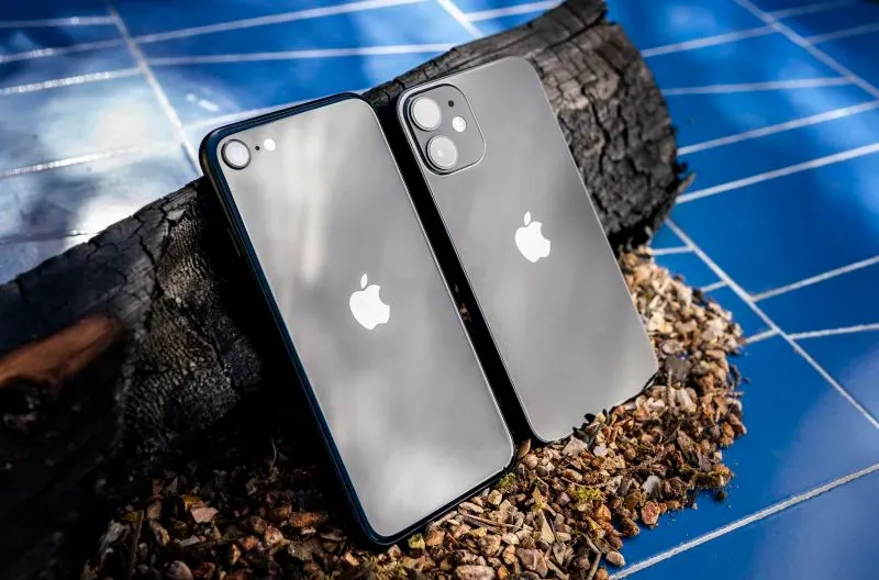 هاتف iPhone 16e الجديد من أبل، بجانب iPhone XR، يظهران مع تصميم أنيق على خلفية طبيعية، مما يبرز استراتيجيات أبل في السوق.