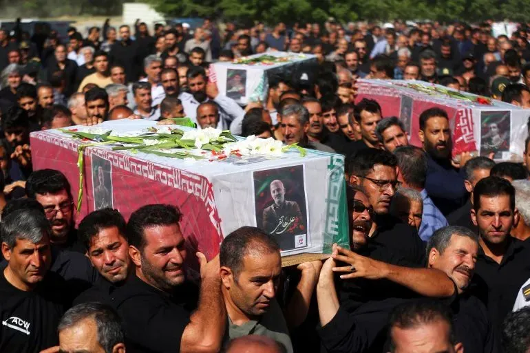مراسم تشييع حاشدة في طهران، حيث يحمل المشيعون نعوش ضحايا الهجمات الإسرائيلية، مع تزيين النعوش بالزهور وصور الراحلين.