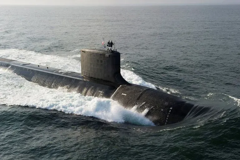 غواصة نووية تبحر في المحيط، مع ظهور طاقمها على السطح، تعكس التعاون العسكري بين أستراليا والولايات المتحدة والمملكة المتحدة.