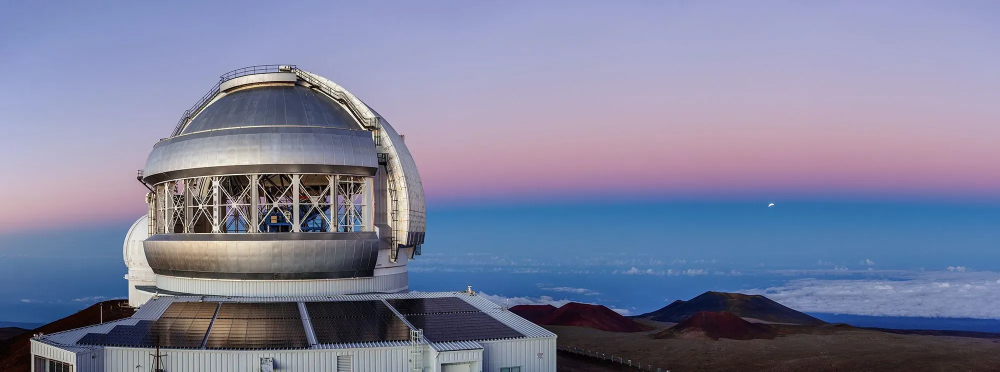 تلسكوب الجوزاء الشمالي في هاواي، يُستخدم لرصد النجم بيتلجوز، مع سماء ملونة في الأفق تعكس أهمية البحث الفلكي.