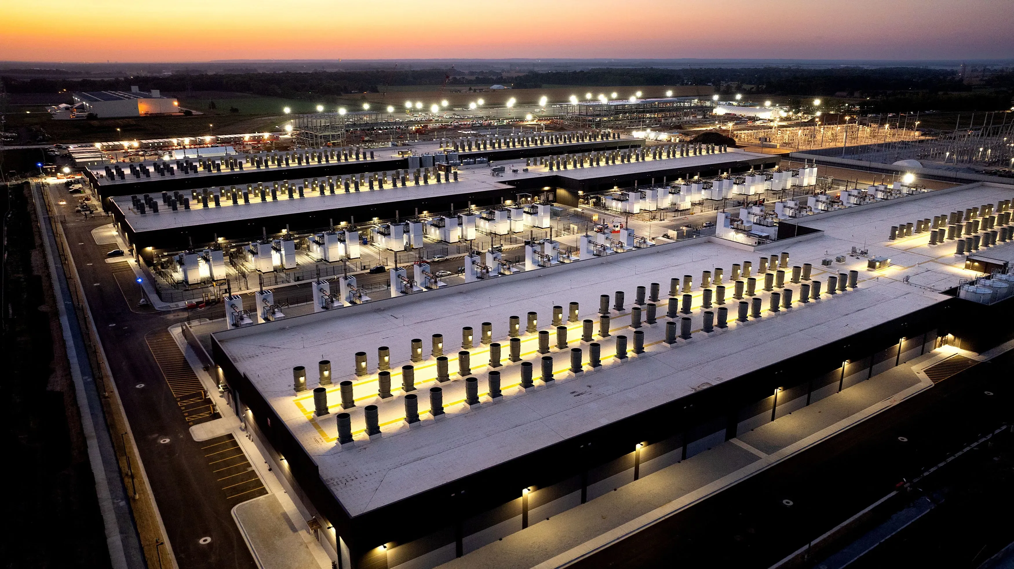 مركز بيانات كبير مضاء في المساء مع صفوف من المعدات الكهربائية، يعكس تأثير أزمة الكهرباء على الفواتير في الولايات المتحدة.