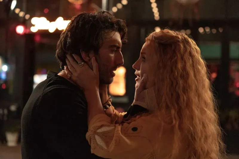مشهد من مسلسل "It Ends With Us" يظهر شخصيتين تتبادلان نظرات رومانسية في أجواء دافئة، مما يعكس توتر الحب وسط الأزمات القانونية.