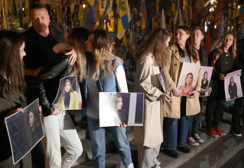 تجمع عدد من الأشخاص في مظاهرة، يحملون صورًا للصحفية الأوكرانية فيكتوريا روشينا، تكريمًا لذكراها بعد وفاتها في الأسر الروسي.