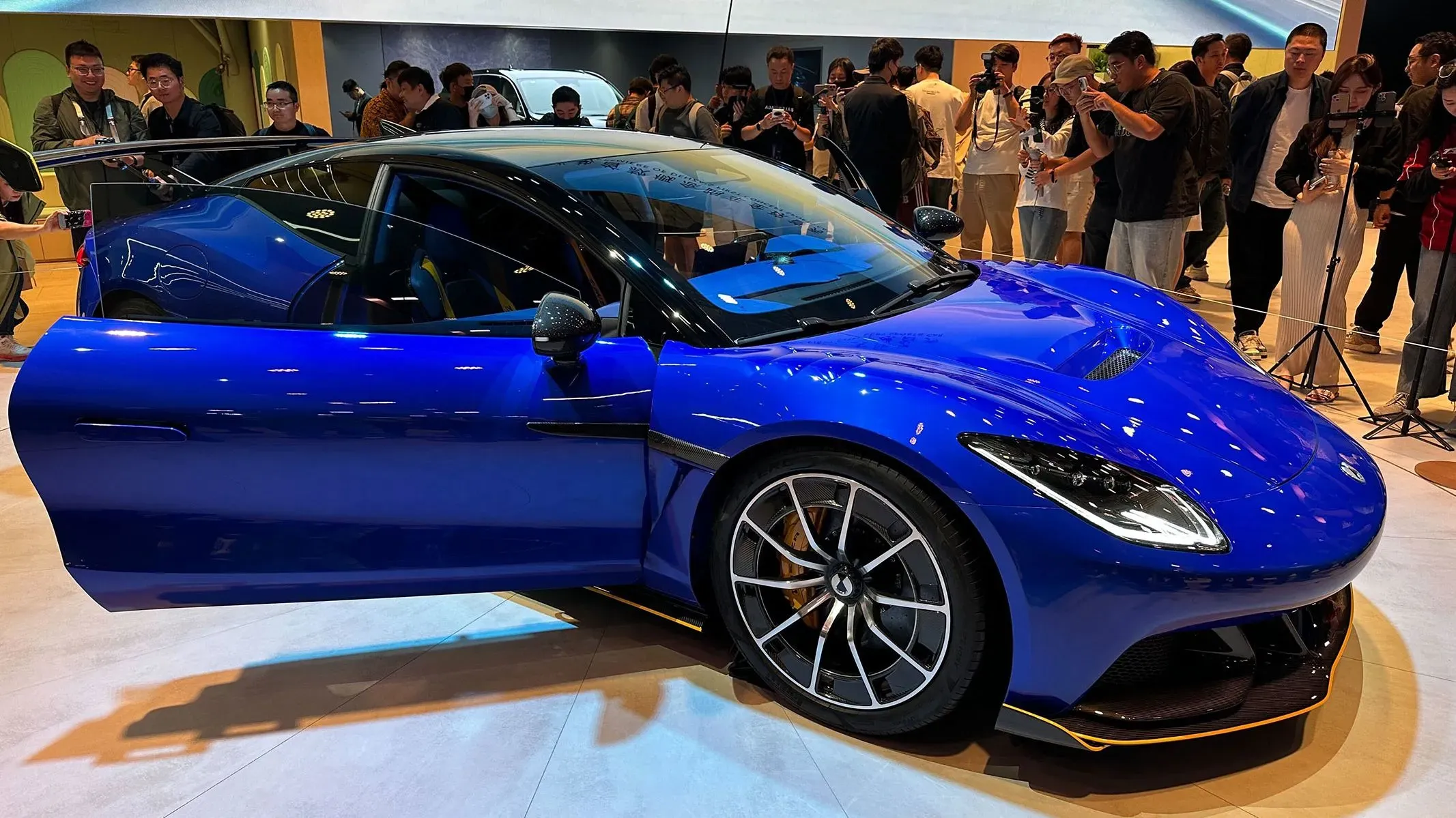 سيارة دينزا Z الفاخرة باللون الأزرق الغامق تعرض في معرض شنغهاي للسيارات، محاطة بجمهور من الصحفيين والزوار.