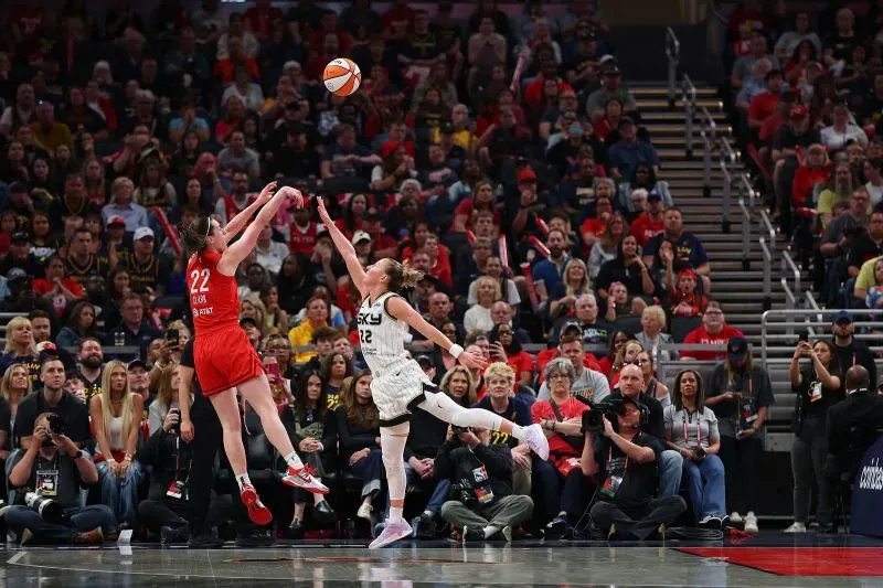 لقطة حماسية من مباراة كرة السلة بين إنديانا فيفر وشيكاغو سكاي، حيث تسجل لاعبة سكاي رمية تحت ضغط من لاعبة فيفر، وسط جمهور متحمس.