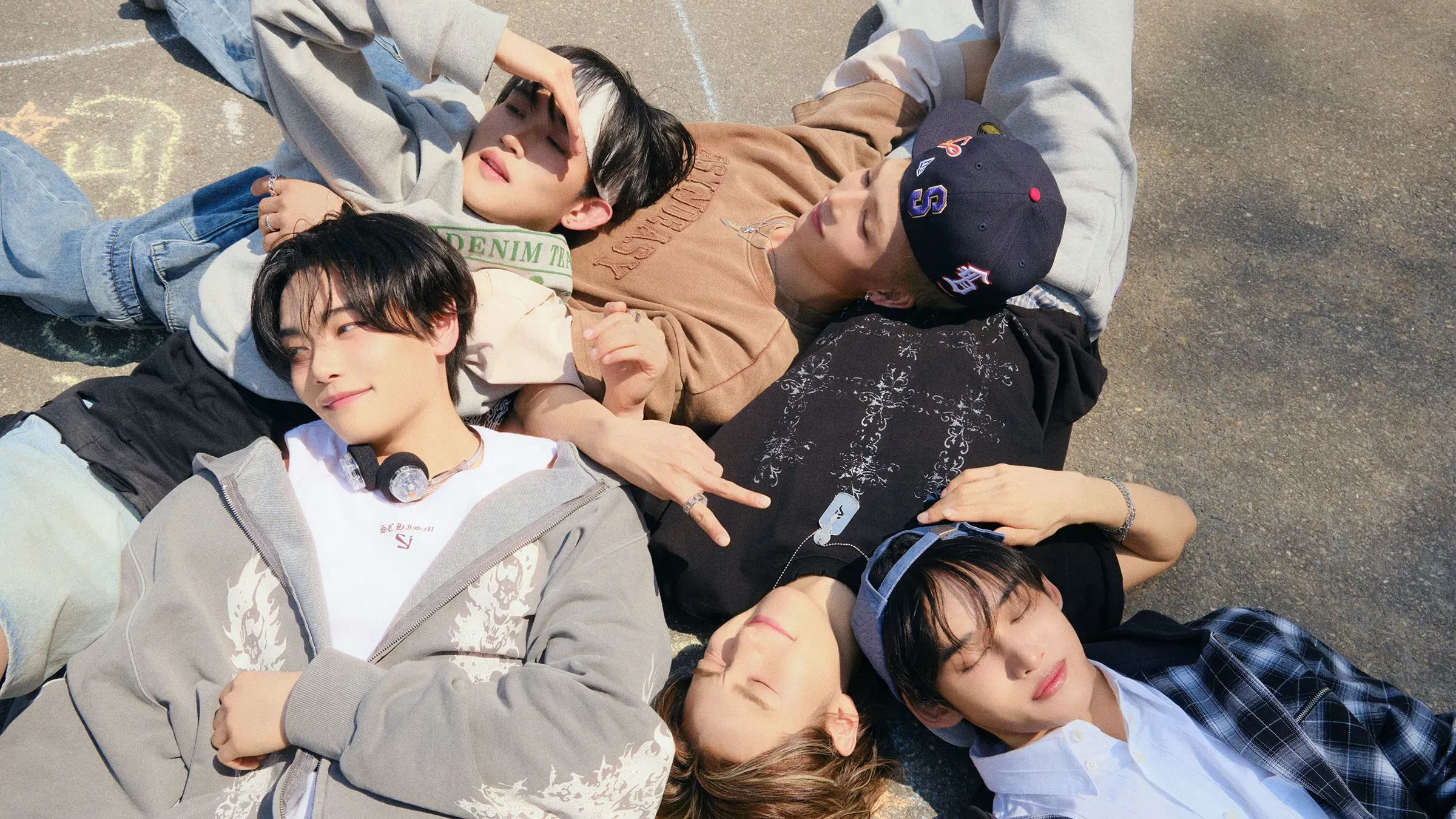 مجموعة من خمسة شبان من فرقة 1VERSE مستلقين معًا في وضع مريح، يعكسون روح الصداقة والطموح في عالم الكيبوب.