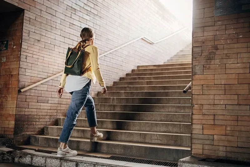 امرأة تتسلق السلالم، تمثل فكرة "وجبات التمارين الرياضية" لتعزيز اللياقة البدنية والصحة العامة.