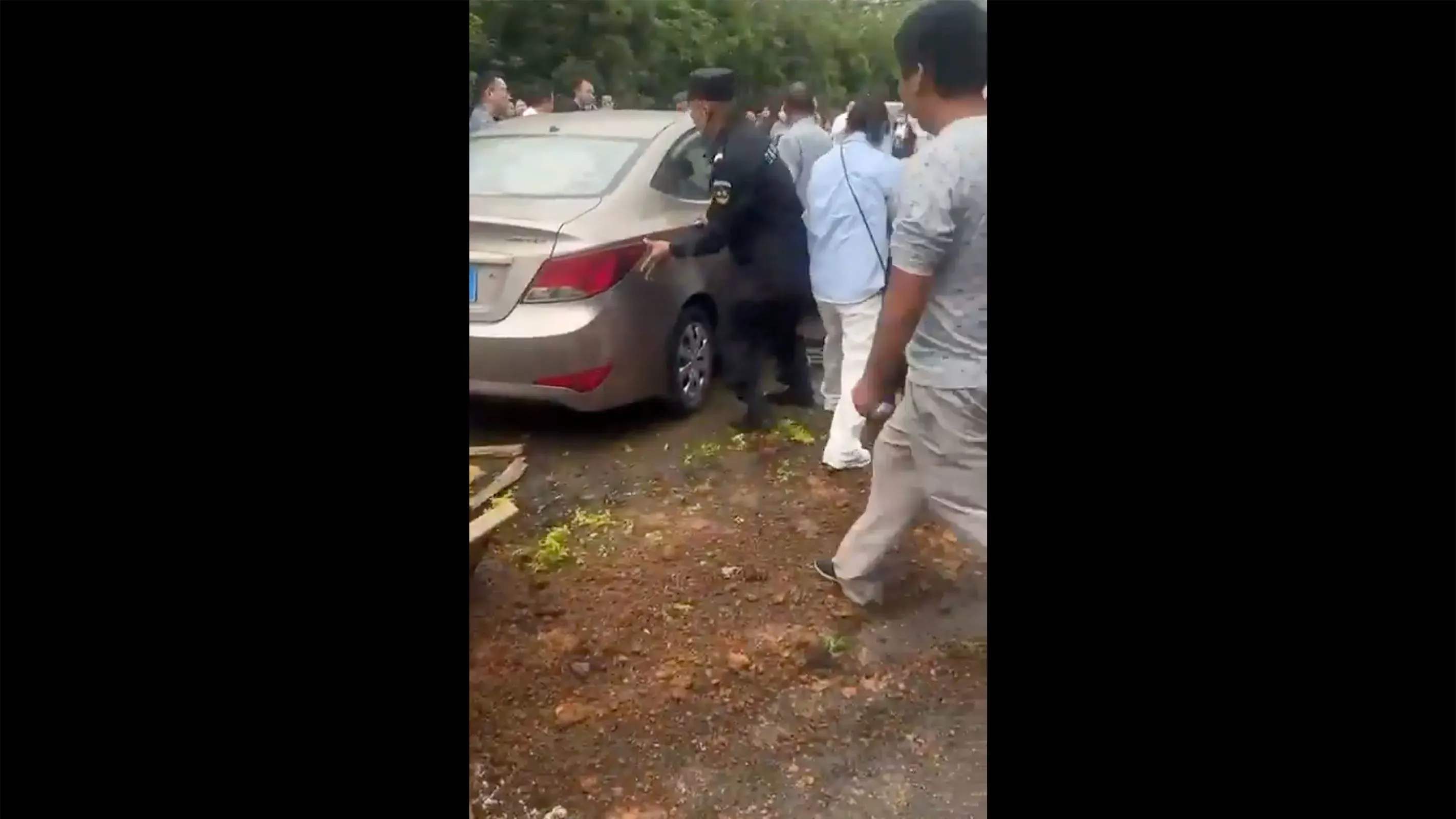 حادثة اصطدام سيارة بحشد من الناس خارج مدرسة في جينهوا، مع وجود رجال الشرطة والمارة يساعدون الضحايا.