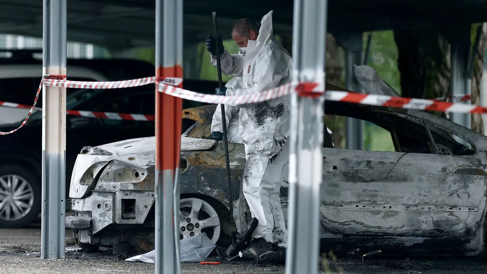 تحقيق في موقع حريق سيارات في سجن تاراسكون، حيث يرتدي المحققون ملابس خاصة. الهجمات مرتبطة بزيادة العنف في السجون الفرنسية.