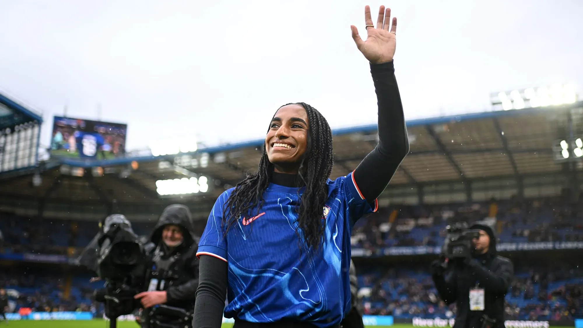 نعومي جيرما، مدافعة منتخب الولايات المتحدة، تلوح بيدها لجماهير تشيلسي أثناء تقديمها في ستامفورد بريدج، مرتدية القميص الأزرق.