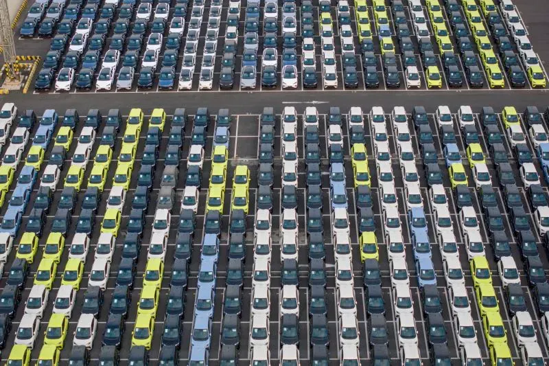 صف من السيارات الكهربائية الملونة مصطفة بشكل منظم في ساحة انتظار، مما يعكس هيمنة الصين في سوق السيارات الكهربائية العالمية.