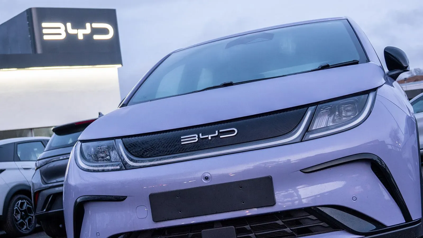 سيارة كهربائية من شركة BYD بلون أرجواني، مع ظهور شعار الشركة في الخلفية، تعكس التنافس المتزايد في سوق السيارات الكهربائية.