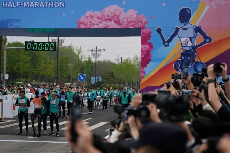 سباق نصف ماراثون في الصين يضم روبوتات ثنائية الأرجل ومتسابقين بشريين، مع حشد من المشاهدين والكاميرات.