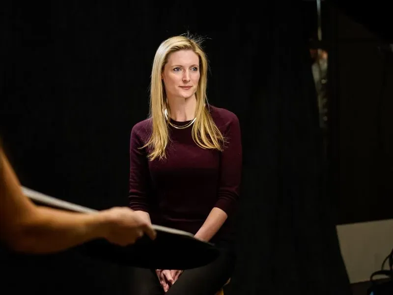 ألكسندرا ريف تجلس أمام كاميرا في جلسة تصوير، مع خلفية داكنة، تعبر عن مشاعر الارتباط والصداقة العميقة.