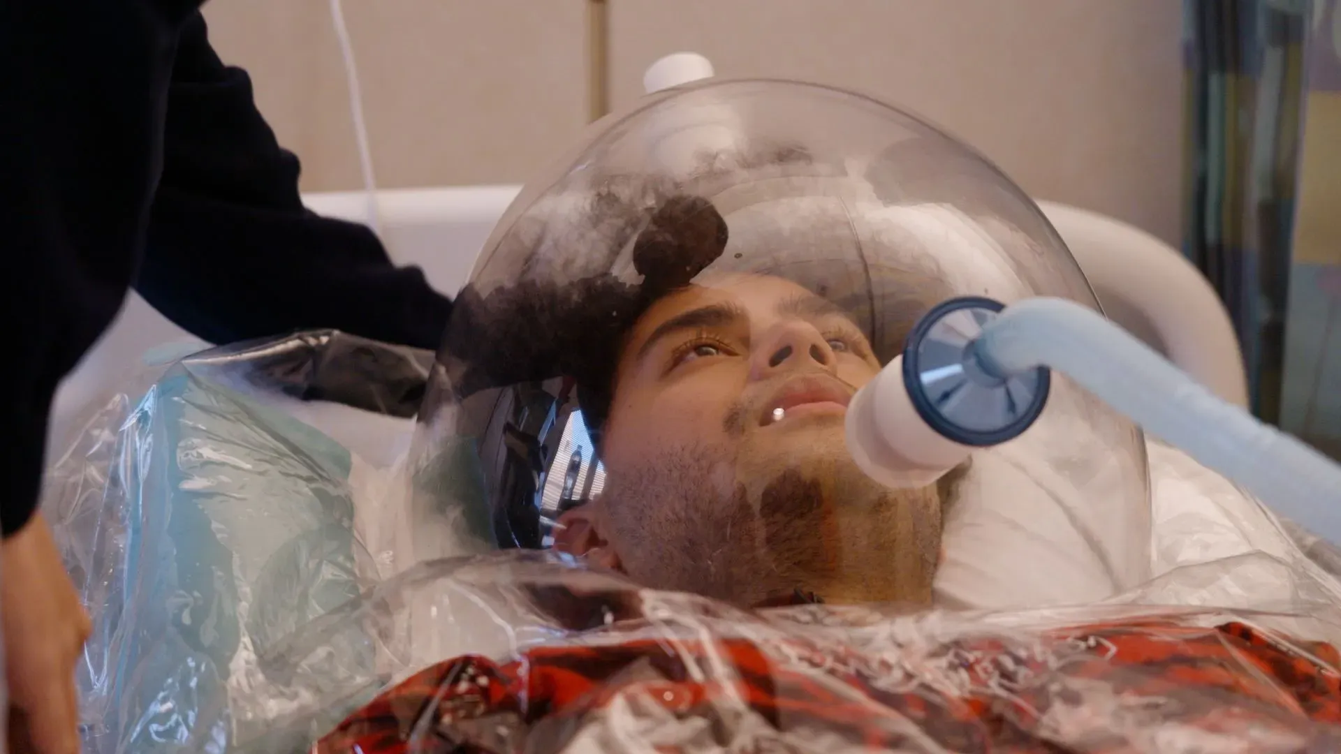 رجل يرتدي غطاءً شفافًا حول رأسه، يتلقى علاجًا طبيًا، مما يعكس تأثير المواد المضافة في الأطعمة على الصحة.