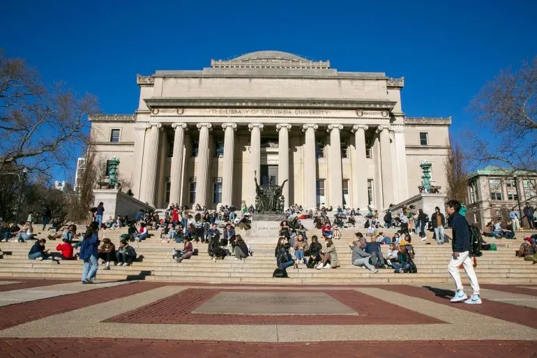 طلاب جامعة كولومبيا يجلسون على الدرجات أمام مبنى الجامعة التاريخي، في إطار مناقشات حول قضايا معاداة السامية والاحتجاجات.