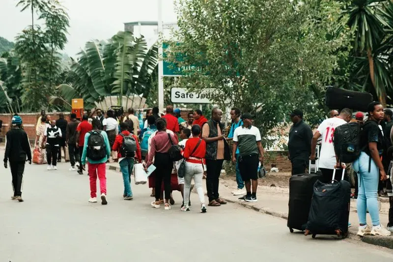 تشهد الحدود بين الكونغو ورواندا تدفقًا للنازحين، مع تجمع عائلات تحمل الأمتعة بالقرب من علامة تشير إلى "مكان آمن" وسط تصاعد العنف.