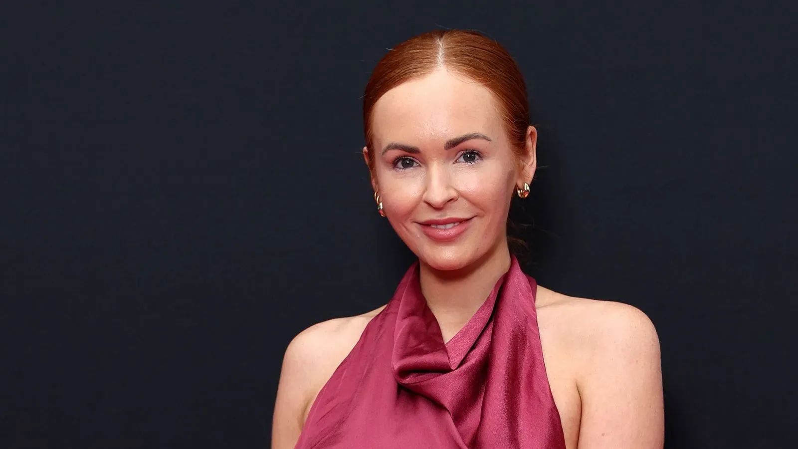 صورة لبرك بيلامي، كاتبة الطبخ الشهيرة، ترتدي فستانًا أنيقًا بلون خمري، تظهر بابتسامة في حدث رسمي.