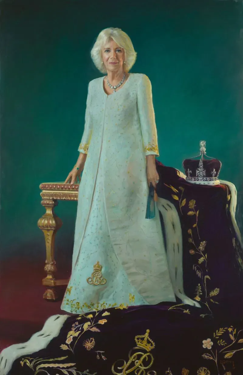 تظهر الملكة كاميلا في ملابس التتويج، بجانب تاج ودثار ملكي، في لوحة رسمها بول بيني، مع خلفية خضراء.