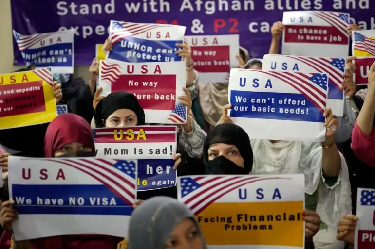 محتجون يحملون لافتات تطالب بدعم اللاجئين الأفغان، مع وجود شعارات تتعلق بالهجرة وحقوق الإنسان، في سياق حكم قضائي أمريكي.