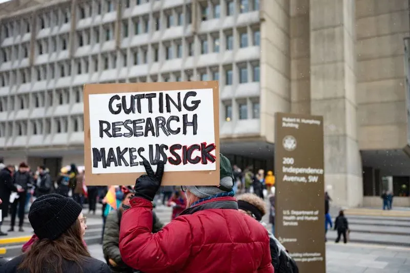 لافتة تحمل عبارة "تخفيض الأبحاث يجعلنا مرضى" خلال احتجاج أمام وزارة الصحة والخدمات الإنسانية في واشنطن.