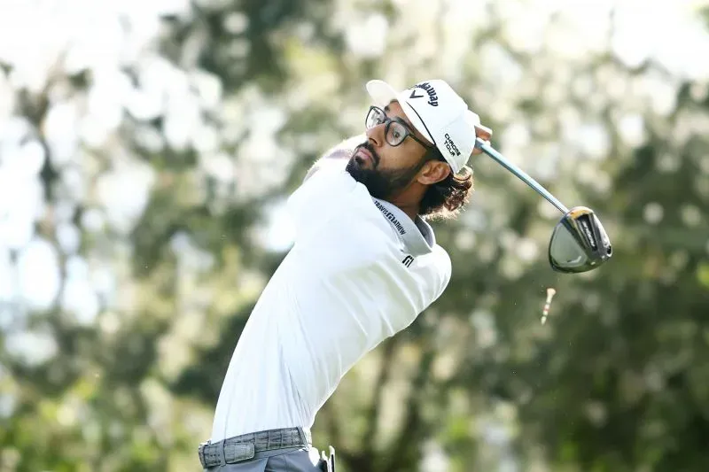 لاعب جولف يضرب الكرة في بطولة TPC Sawgrass، مع خلفية طبيعية خضراء، يعكس تركيزه وأدائه المتميز.