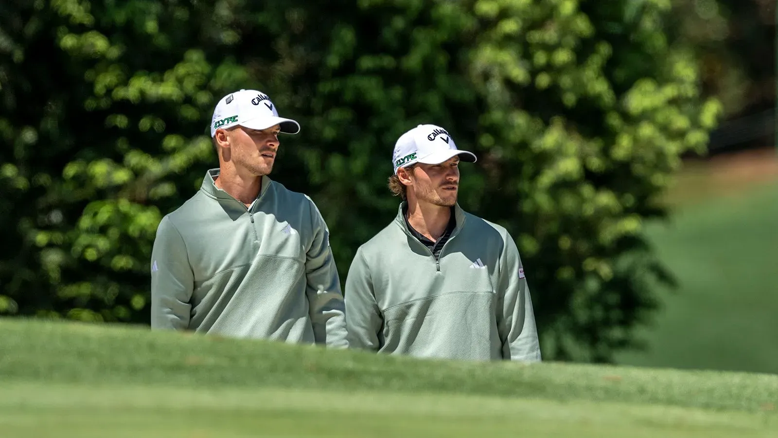 توأم هويغارد، نيكولاي وراسموس، يرتديان ملابس متشابهة أثناء المؤتمر الصحفي لبطولة الماسترز، مع خلفية خضراء من الأشجار.