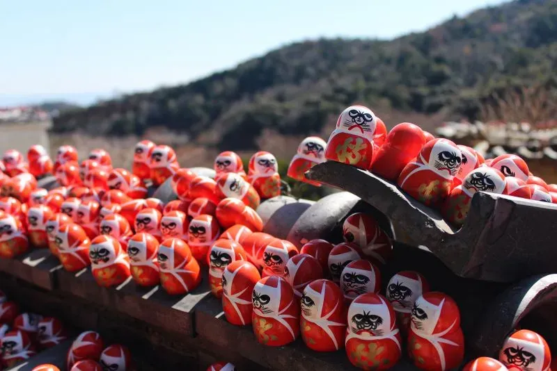 مجموعة من دمى داروما الحمراء مستندة على بعضها، تظهر في معبد كاتسو-جي، رمز الحظ والعزيمة في الثقافة اليابانية.