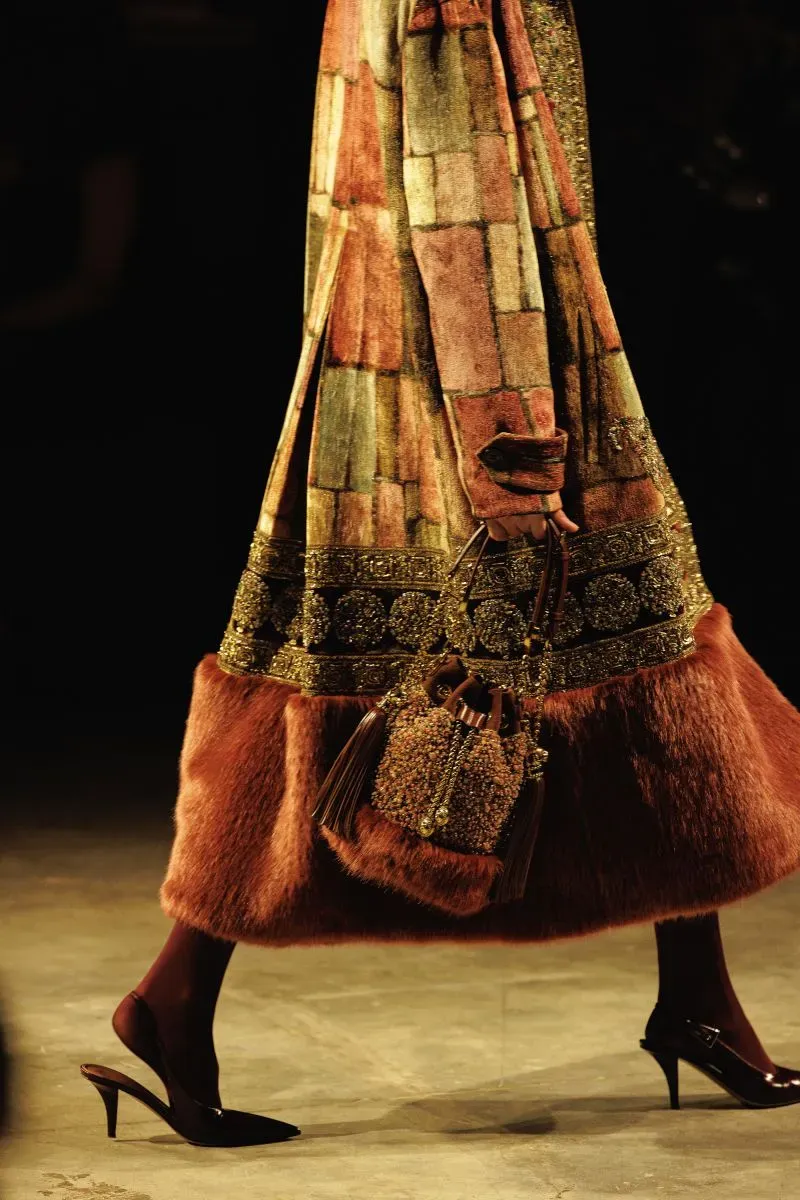 تصميم هندسي أنيق لعرض أزياء سابياساتشي موخرجي، يظهر طرازاً مزيناً بألوان دافئة وقطع فاخرة، تبرز الثقافة الهندية المعاصرة.