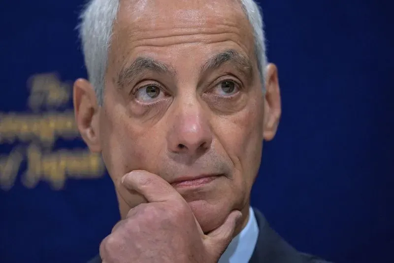 صورة لرجل في بدلة، يبدو عليه التفكير والتأمل، يتحدث في مؤتمر صحفي حول السياسة الانتخابية المقبلة.