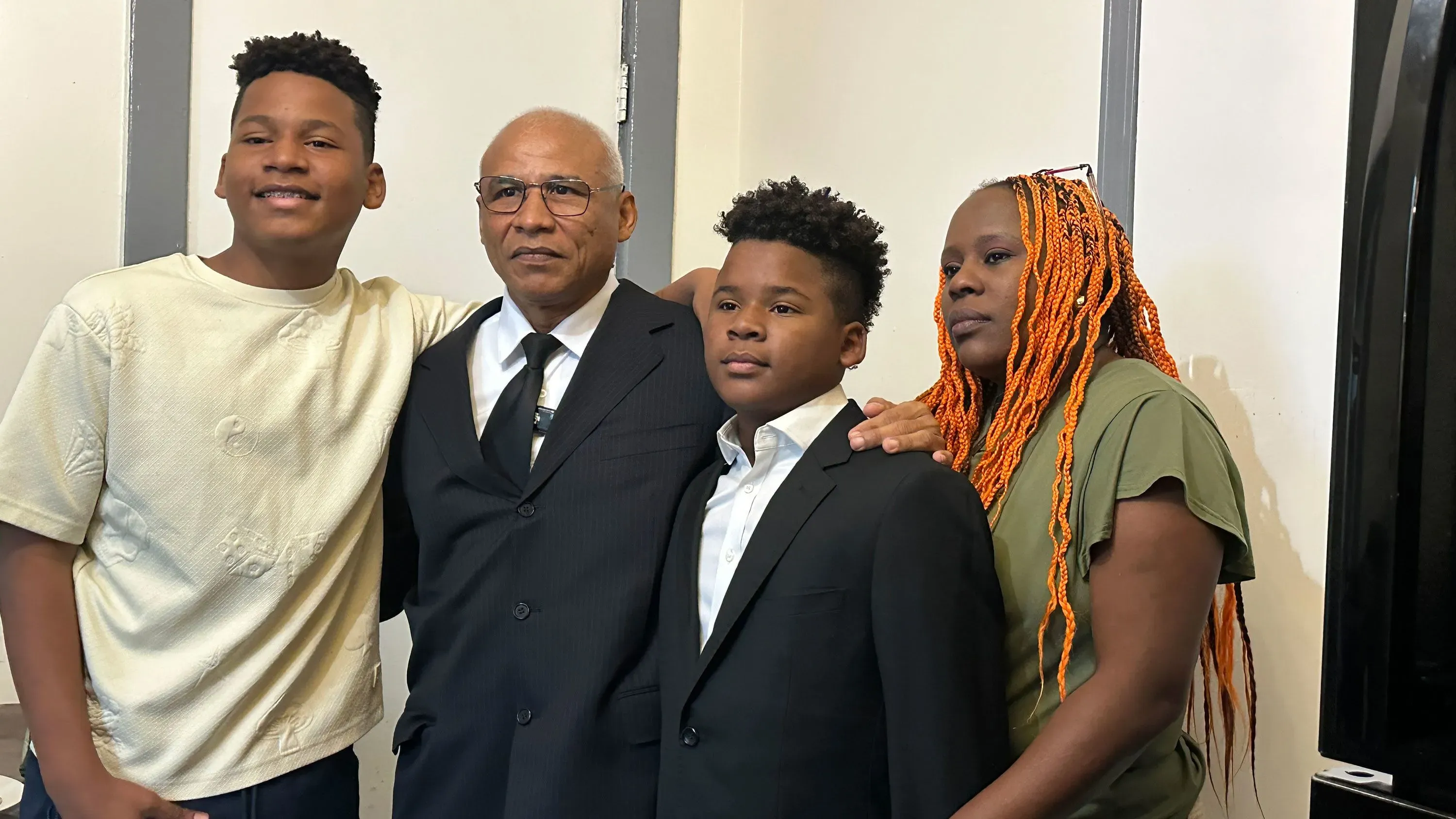 عائلة تتكون من ثلاثة أطفال ورجل مسن يرتدون ملابس رسمية، يظهرون معًا في مناسبة خاصة، تعكس الروابط الأسرية والتقاليد.