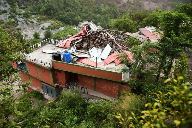 منزل مدمر في كشمير بعد تعرضه لقذائف مدفعية، يظهر الأضرار الكبيرة والخراب وسط الطبيعة المحيطة، تعبيراً عن النزاع المستمر بين الهند وباكستان.