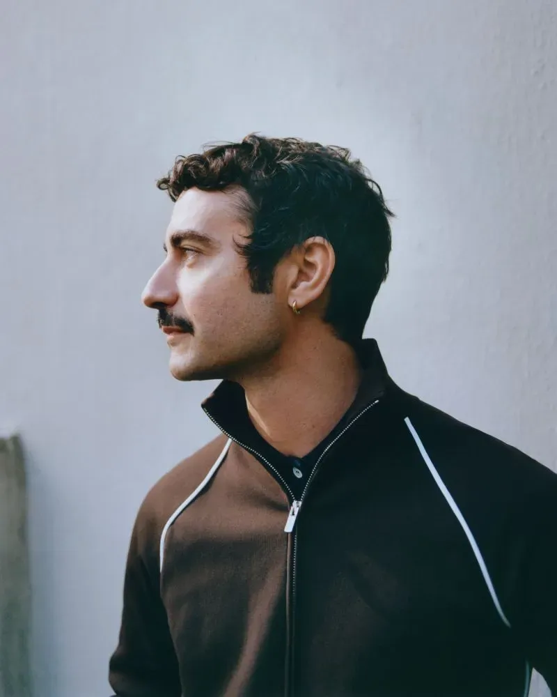 داريو فيتالي، المدير الإبداعي الجديد لفيرساتشي، ينظر إلى الجانب مع تعبير جاد، مرتديًا سترة داكنة.