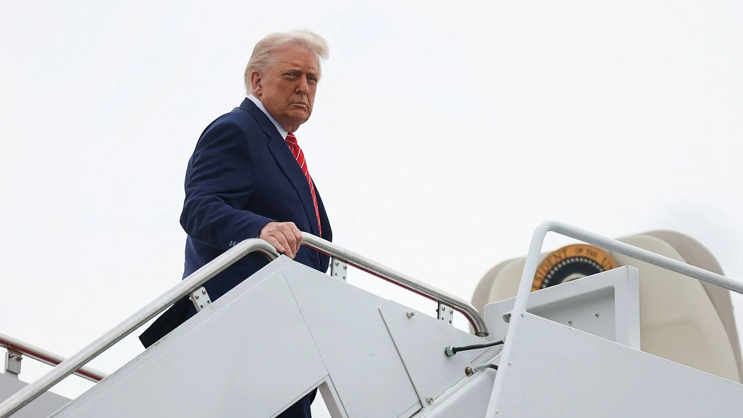 ترامب يتجه نحو الطائرة، مع تعبير جاد، في سياق تصاعد التوترات بين روسيا وأوكرانيا وتأثير السياسة الأمريكية.