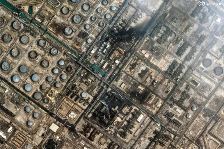 صورة جوية لموقع صناعي يحتوي على خزانات نفطية ومنشآت، مع وجود آثار حريق في أحد المناطق، تعكس تصاعد التوترات في الشرق الأوسط.