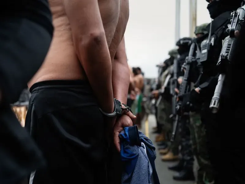 رجل مقيد اليدين يقف أمام قوات الأمن المسلحة في الإكوادور، في سياق جهود الحكومة لمكافحة العصابات.